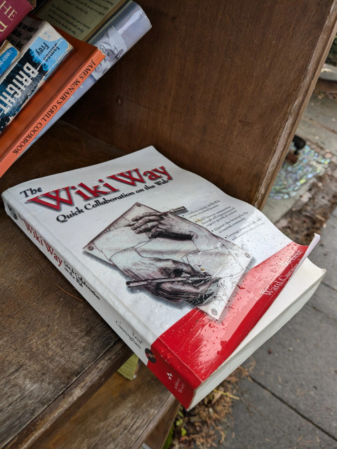 Photo of a soggy paperback copy of The Wiki Way by Leuf and Cunningham that's been left on an outdoor bookshelf with poor rain protection