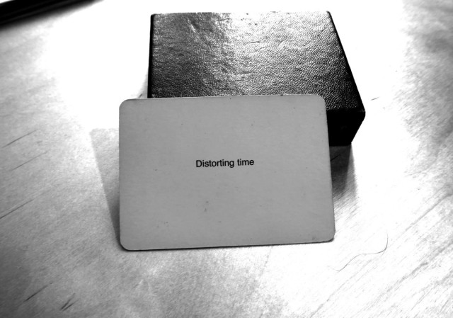 A black-and-white photo of an Oblique Strategy card. The card reads: 'Distorting time'.