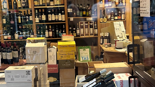 cluttered wine shop with a CRT monitor covered entirely in post-it notes