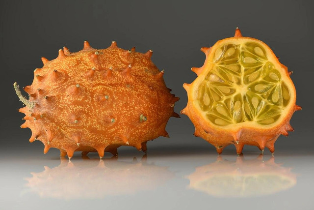 Horned melon picture, one is pointing to the left and one is cross-section open.  The whole one looks like you could put a little eye on it and it would be the cutest little creature