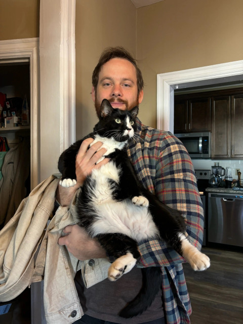 Me in a flannel holding a big tuxedo cat.