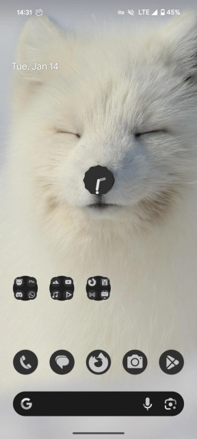 A screenshot of my pixel launcher homescreen. The wallpaper is a cute arctic fox with closed eyes. There's a round clock widget right where the nose is.