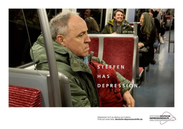 Photograph taken in a subway, text above a man not smiling at all : STEFFEN HAS DEPRESSION.
And another text above a man behind,  laughing with a friend : THIS IS STEFFEN.

Depression isn't as obvious as it seems, Find out more here: deutsche-depressionshilfe.de

From German depression and suicide prevention