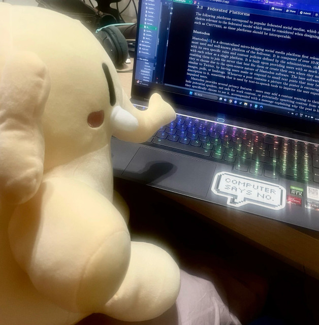 Mastodon plush sitting in a chair looking at a computer screen with text, the heading reads “Mastodon”