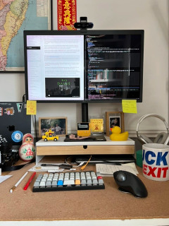 Planck EZ keyboard on a desk with a monitor, a trackball, and other assorted stuff