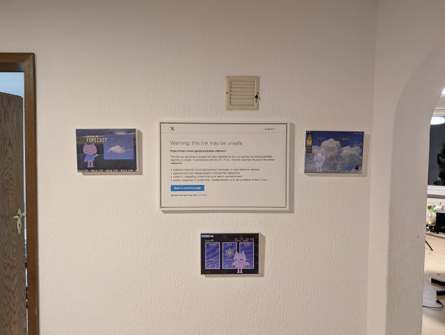 a photo of a wall, in the middle is a framed canvas print of a twitter "this link may be unsafe" popup, it is surrounded by three more way smaller canvas prints of art from the game peklo