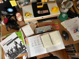 Planck EZ on a desk among books, notebooks, and other things