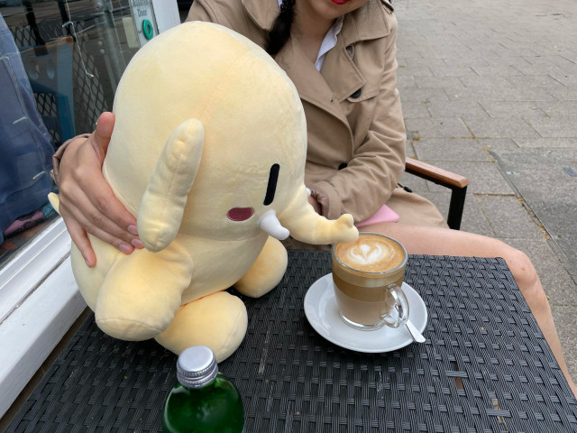 A stuffed Mastodon toy is leaning over to drink some coffee.