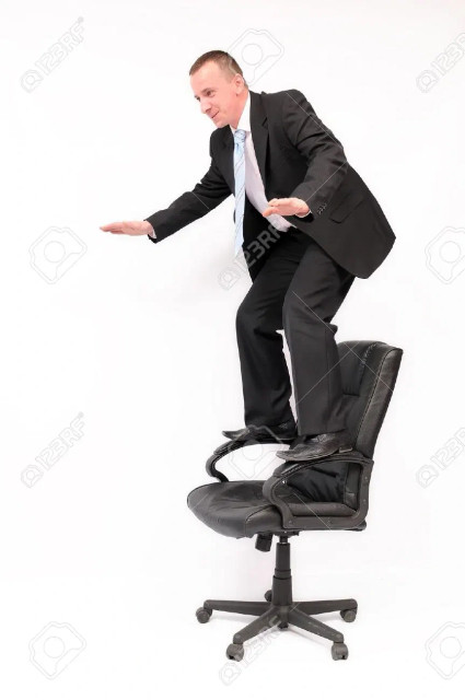 A stock image of a guy in a business suit standing on a chair