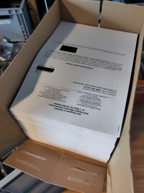 An A4 copy box full of printer paper. The topmost sheet shows a court document.