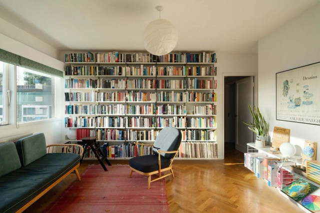 A photo of a living room with a large shelf full of books, taking up an entire wall